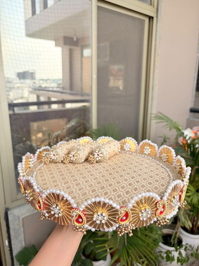 Zari gold pooja thali held up by hand